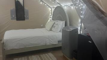 Une chambre confortable, aménagée comme une tente, avec un lit, une petite table et un radiateur.