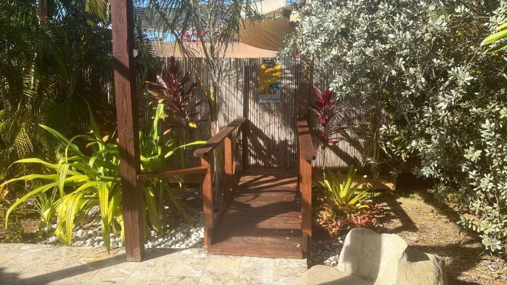 A wooden pathway leading to a building with a signboard.