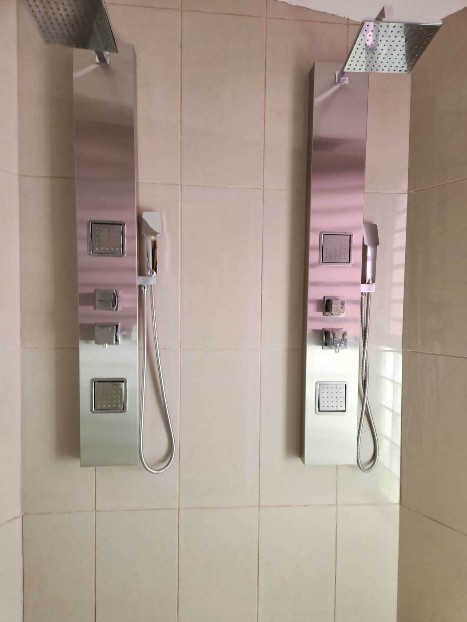 A modern bathroom with two wall-mounted showers, each with a handheld showerhead and a control panel.