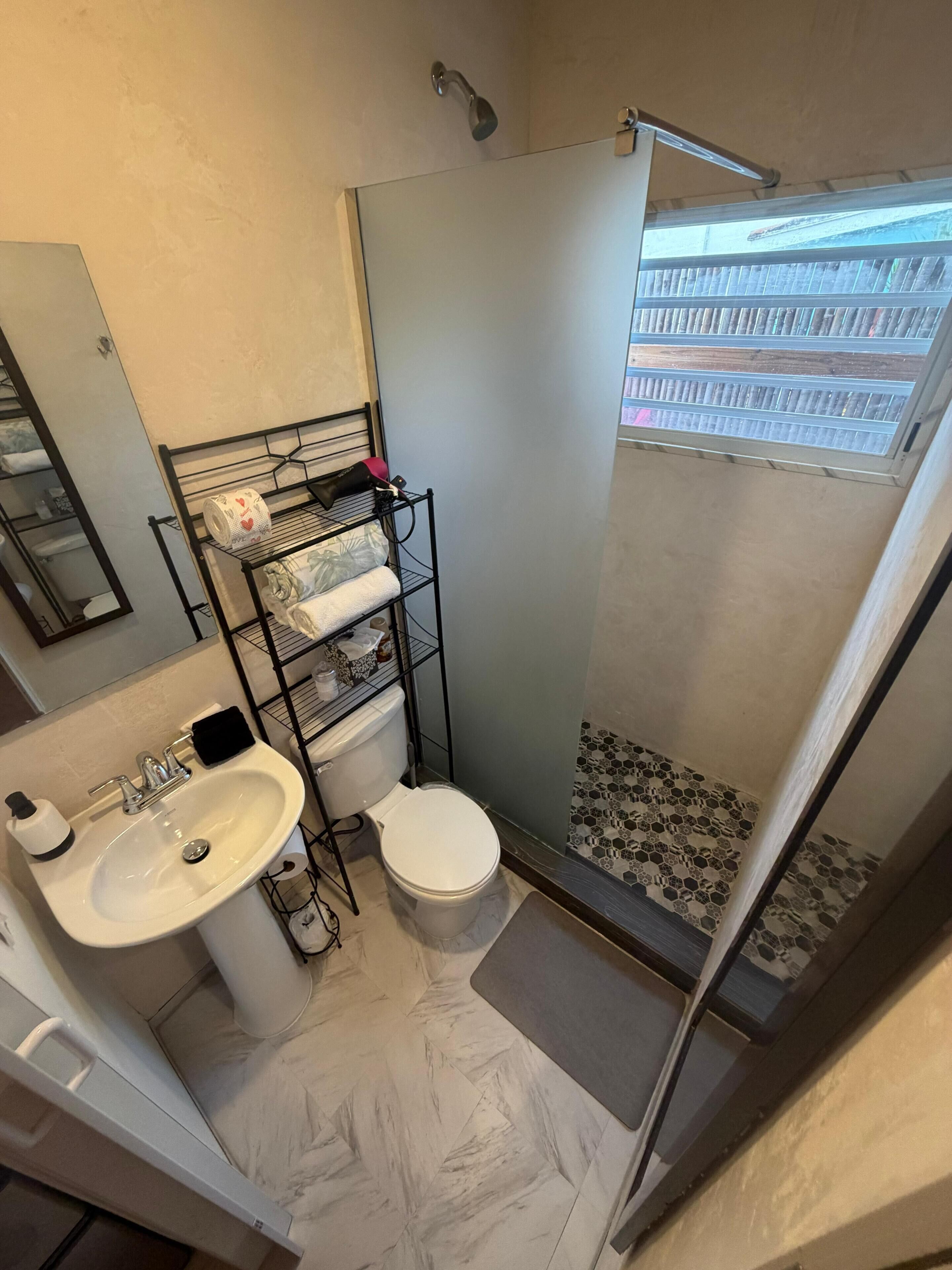A compact bathroom with a sink, toilet, and shower.
