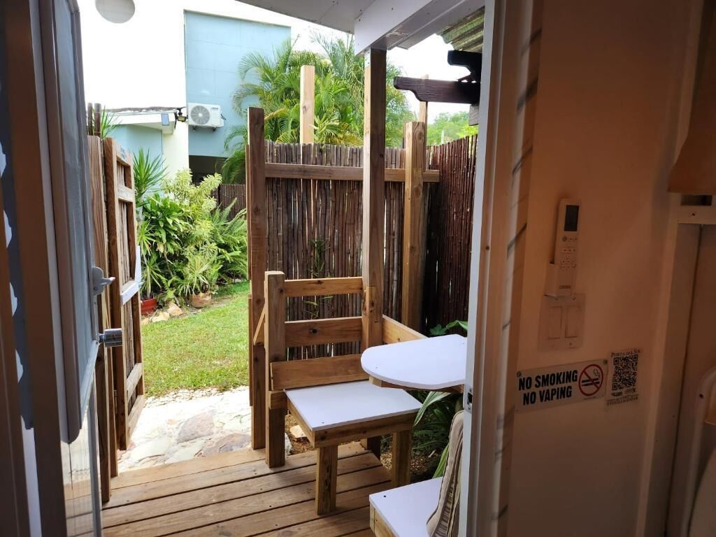 A wooden deck with a table and chairs, a wooden fence, and a sign prohibiting smoking and vaping.