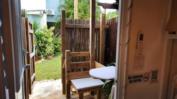 A wooden deck with a table and chairs, a wooden fence, and a sign prohibiting smoking and vaping.