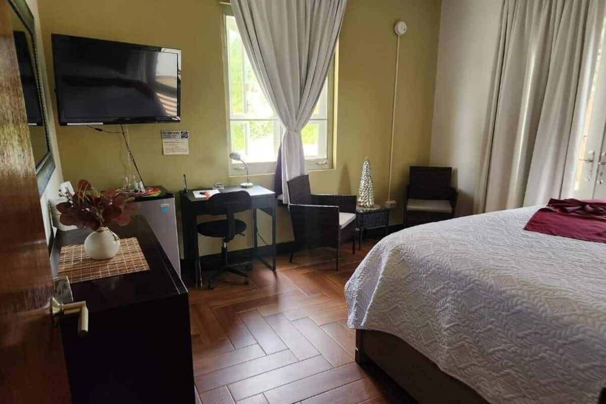 A hotel room with a bed, desk, chair, and a television.