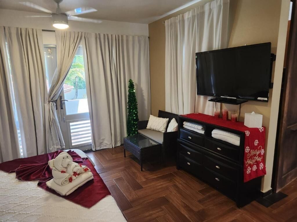 Une chambre d’hôtel avec un lit, une télévision, un bureau, une chaise, une commode et un sapin de Noël.