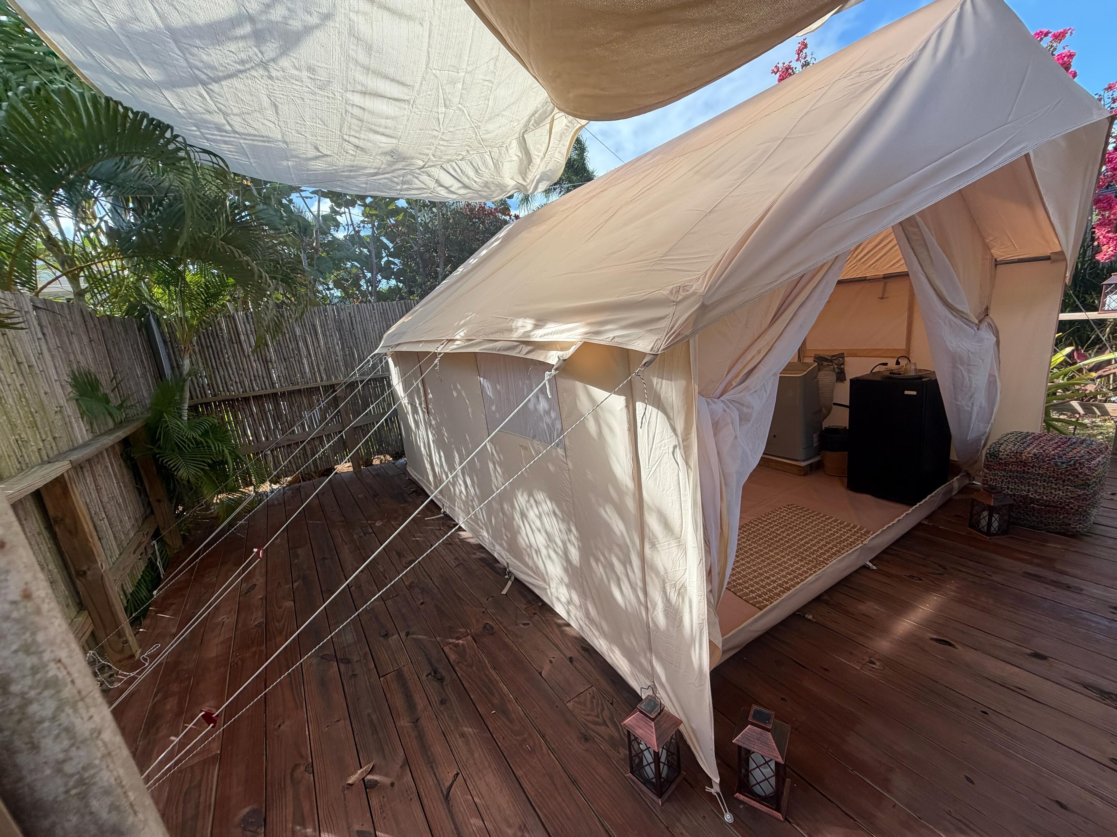A tent with a wooden deck, a speaker, and a lantern.