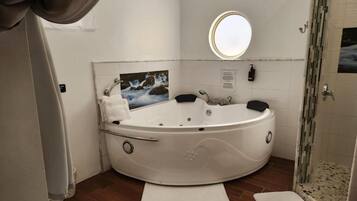 A bathroom with a large, freestanding bathtub, a round mirror, and a shower area.