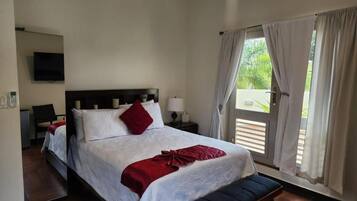 A hotel room with a bed, bedside tables, a TV, and a window with curtains.