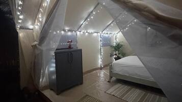 Una carpa con una cama, un mueble pequeño y luces de cuerda.