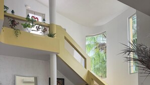 Un amplio espacio habitable con techo alto, una escalera y ventanas grandes.