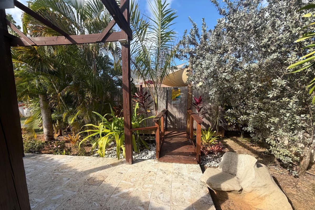 A wooden pergola with a tiled floor leading to a covered area.