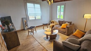 Een woonkamer met een bruine bank, een salontafel, een stoel en een televisie.