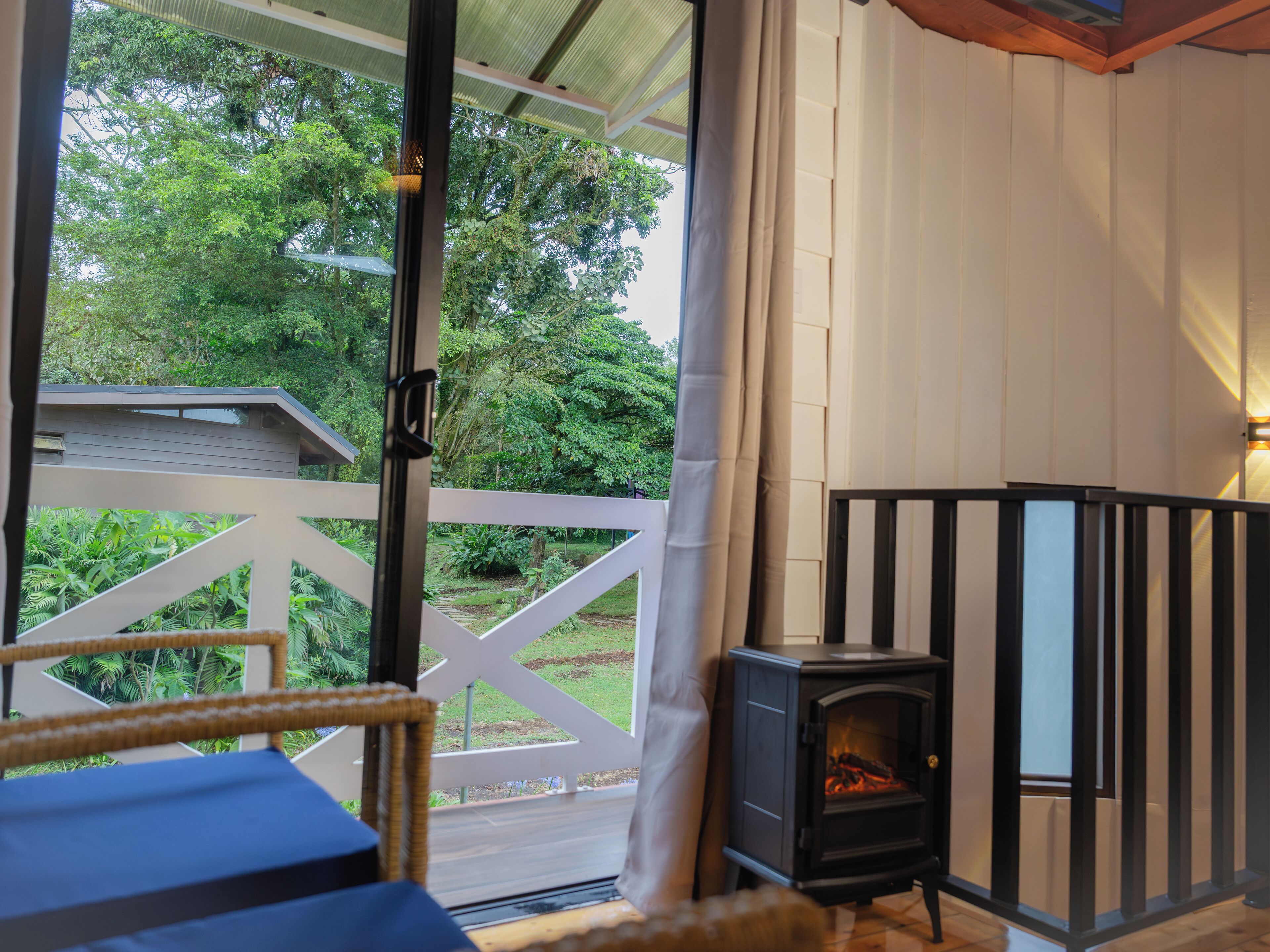 A cozy room with a wooden floor, a white railing, and a black wood-burning stove.