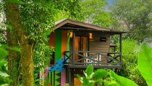 Een boomhut met een kleurrijke buitenkant, omgeven door weelderige begroeiing.