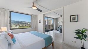 Ett modernt hotellrum med en stor säng, en takfläkt, utsikt över staden och en balkong.