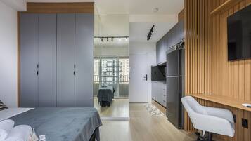 Quarto moderno com cama, guarda-roupa e vista para uma varanda com mesa e cadeiras.