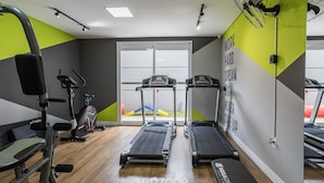 Une salle de sport équipée de tapis de course, d’un vélo d’appartement et d’appareils de musculation.