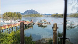 Ein Steg mit Booten, ein Haus auf Stelzen und Berge im Hintergrund.