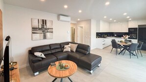 Uma sala de estar moderna com um sofá de couro escuro, uma mesa de centro redonda de madeira e um quadro minimalista na parede.