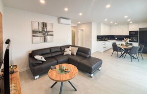 A modern living room with a dark leather sofa, a round wooden coffee table, and a minimalist painting on the wall. - Lovely apartment in Tucepi with house sea view (Tucepi)