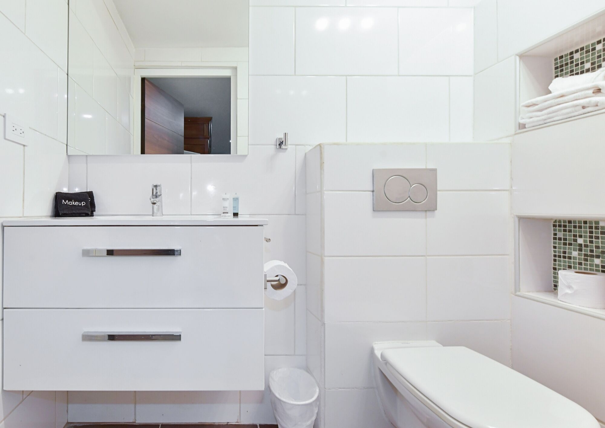 Un baño moderno con tocador blanco, inodoro y zona de ducha.