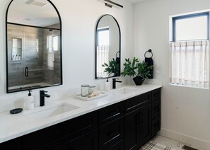 A modern bathroom with two sinks, black cabinets, a large mirror, and a potted plant. - Luxury 5BR with hot tub, heated game garage, mini golf, outdoor projector (Denver)