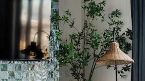 Ein gemütliches Wohnzimmer mit Kamin, einem weißen Sessel, einer Stehlampe und einem kleinen Tisch mit Buch und Kerzen.