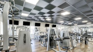 A gym with various exercise machines, wooden flooring, and a checkered ceiling. - Smith Mountain Lake Studio | Pool, Beach & Trails (Huddleston)