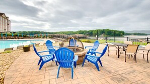A poolside area with blue Adirondack chairs, a fire pit, and a view of a lake. - Smith Mountain Lake Studio | Pool, Beach & Trails (Huddleston)