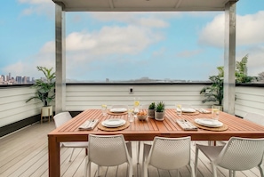 A wooden deck with a table set for four, overlooking a city skyline. - Summer rooftop decks, karaoke room, wet bar near Broadway and Gulch (Nashville)