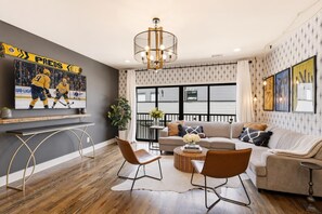 A modern living room with a television, a chandelier, a sofa, and a coffee table. - Nashville home with shuffleboard game room near Belmont, sleeps 12 (Nashville)