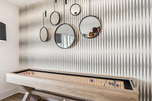 A foosball table with a wooden base and a striped wall with mirrors above it. - Nashville sleeps 12 home near Belmont with game room, shuffleboard & balcony (Nashville)
