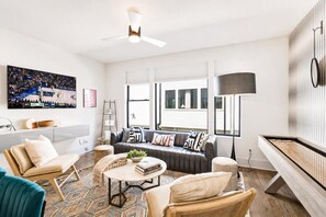 Un salon moderne comprenant un canapé, des fauteuils, une table basse et une table de billard.
