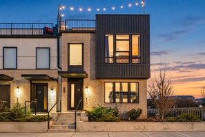 A modern two-story residential building with a balcony, large windows, and a well-lit entrance. - 4-bedroom Nashville townhome sleeps 12 near Centennial Park & Parthenon (Nashville)