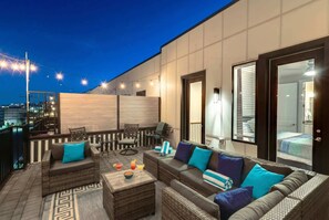 A rooftop terrace with wicker furniture, a coffee table, and a view of the cityscape. - Nashville summer getaway: rooftop deck, game room, 4br sleeps 12 (Nashville)