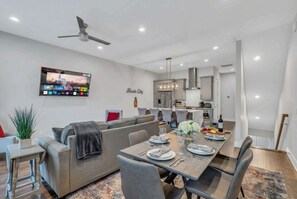 Ein modernes Wohnzimmer mit Essbereich, einer Küche und einem Deckenventilator.