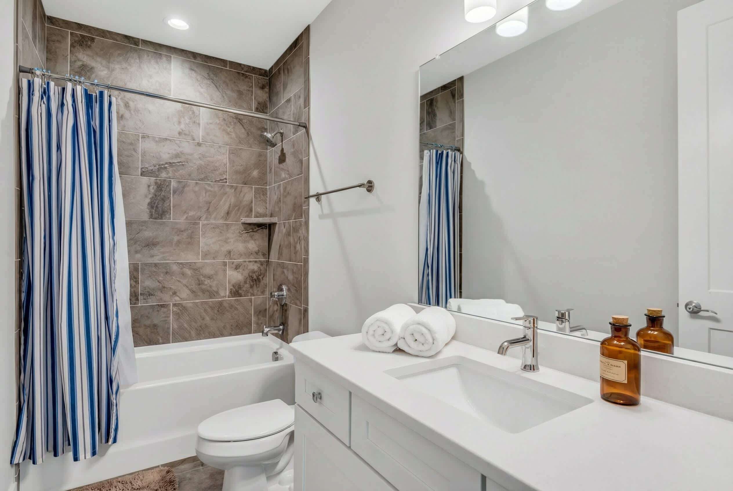 Uma casa de banho moderna com chuveiro, sanita e lavatório.