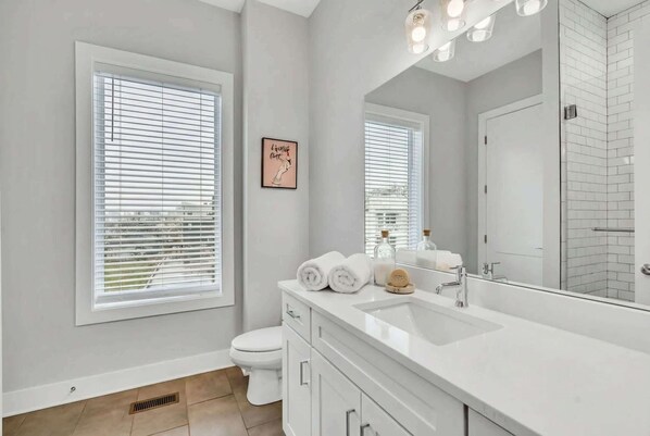 A modern bathroom with a large mirror, white vanity, and a toilet. - Nashville family townhome with rooftop deck & game room, sleeps 12 (Nashville)