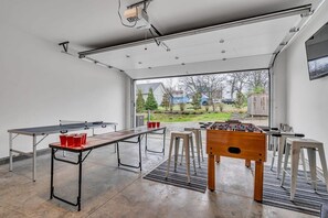 A spacious indoor area with a ping pong table, foosball table, and stools. - Nashville family townhome with rooftop deck & game room, sleeps 12 (Nashville)