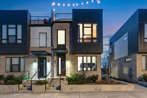 A modern multi-story residential building with a brick facade, large windows, and a balcony. - Nashville summer getaway: rooftop deck, game room, 4br sleeps 12 (Nashville)