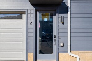 Un portail de garage portant le numéro 1112, un véhicule garé à l’intérieur et un luminaire fixé au mur.