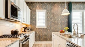 Una cocina moderna con una isla central, electrodomésticos de acero inoxidable y un salpicadero con estampado geométrico.