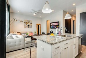 A modern kitchen with a granite countertop, white cabinetry, and a built-in island with a sink. - Fall in Nashville: 3-story home with ping pong lounge, sleeps 12 (Nashville)