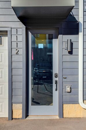 A modern building entrance with a glass door, a keypad lock, and a small mailbox. - Summer rooftop deck, ping pong lounge, skyline views near Broadway (Nashville)