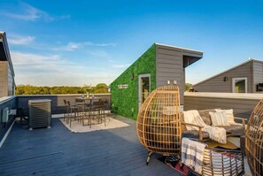 A rooftop deck with a dining area, a green wall, and a lounge with wicker chairs. - Fall in Nashville: Ping Pong Lounge house, sleeps 12, 4 baths (Nashville)