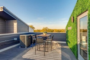 A rooftop patio with a table and chairs, an air conditioning unit, and a green wall. - Fall in Nashville: Ping Pong Lounge house, sleeps 12, 4 baths (Nashville)