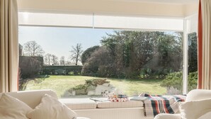 Un salon chaleureux avec une grande fenêtre donnant sur un jardin bien entretenu.