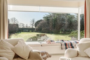 Ein gemütliches Wohnzimmer mit einem großen Fenster und Blick auf einen gepflegten Garten.