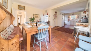Une cuisine spacieuse avec un coin repas, des meubles en bois et un sol carrelé.