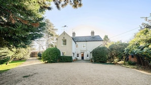 Une maison à deux étages avec une allée en gravier menant à la porte d’entrée.