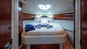 Ein gemütliches Schlafzimmer mit Oberlicht, einem Bett mit Kissen und Decken sowie Holzvertäfelung.